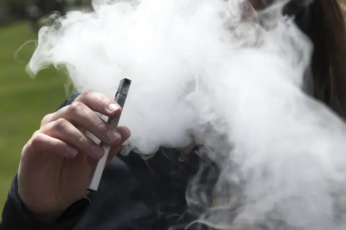 A teen uses a Juul e-cigarette in 2018. New Jersey and 32 other states or territories have announced a settlement against the company that will result in nearly $34 million for the Garden State.